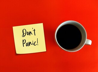 Coffee cup and note on orange background with text written DON'T PANIC , to calm down anxiety and...