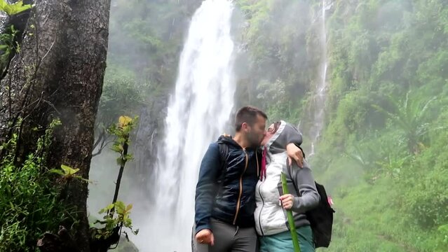 Lovely young couple kissing and celebrating the reach of Materuni waterfall in tropical Tanzania.