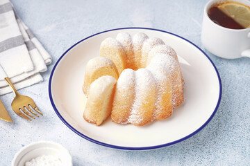 Plate with delicious cake and cup of tea on light background