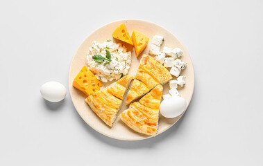 Plate with pieces of delicious cheese pie and ingredients on grey background