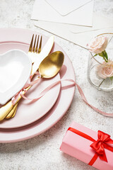 Table setting for Valentine's Day with roses and gift on grunge background, closeup