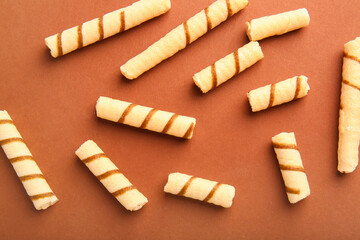 Tasty wafer rolls on brown background
