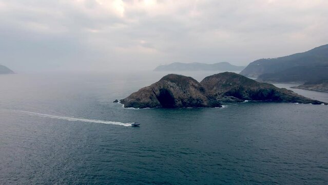 Boat passing by the islands in Hong Kong. Shek O aerial view. Sunset evening. Fast moving boat