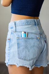Preroll and a lighter in the backpocket of a female model wearing jean shorts