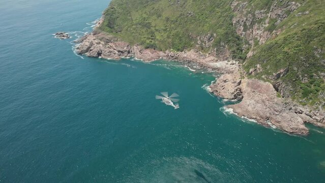 Aerial footage of helicopter flying at the coastline in Hong Kong. Summer day. Cliffs with waves on the island. Tung Lung. Flight.