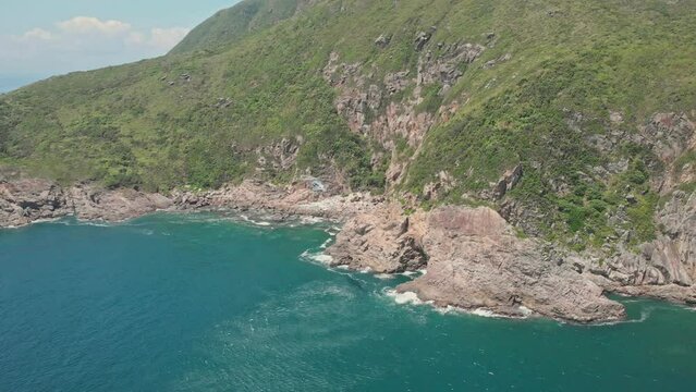 Aerial footage of helicopter flying at the coastline in Hong Kong. Summer day. Cliffs with waves on the island. Tung Lung. Flight.
