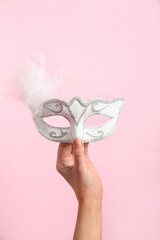 Woman with carnival mask for Purim holiday on pink background