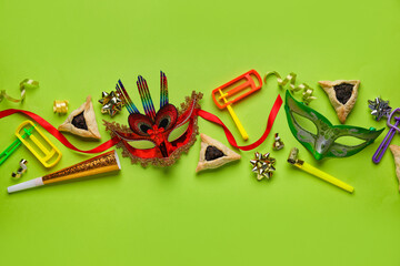 Hamantaschen cookies, carnival masks and rattles for Purim holiday on green background