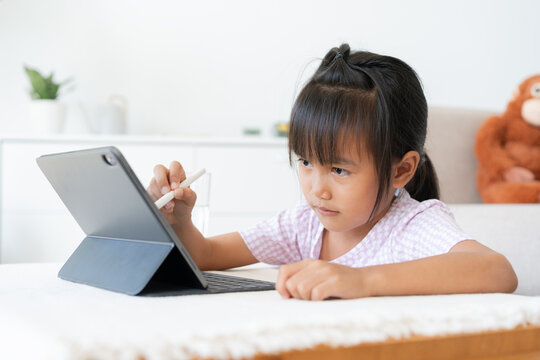 Education. Asian little girl learning and drawing with the online teacher on tablet digital