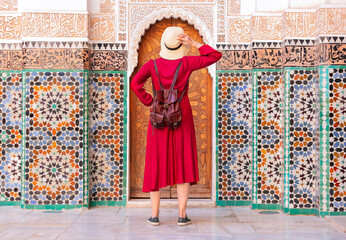 Girl dressing in red with hat looking  Ben Youssef Madrasa in marrakesh in morocco
