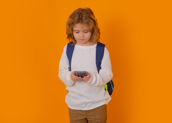 School kid using phone isolated on yellow isolated studio background.