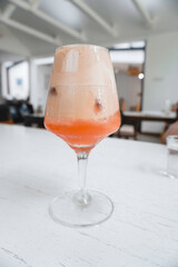 A glass of Iced coffee latte with strawberry syrup and topped with crackers or biscuits