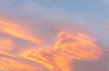 Dramatic cumulus clouds on sunny day at sunset painted in gold with sun. Atmosphere multicolor background or wallpaper