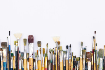 Many brushes for painting on a white background, top view.