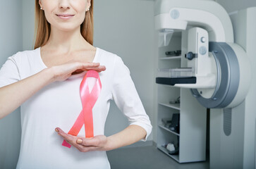 Adult woman holding breast cancer awareness ribbon urging women to have regular breast screening...