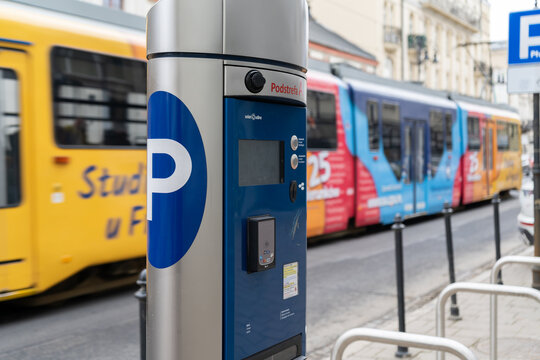 Parking meter (Parkometr or Parkomat) in a paid parking zone of Krak&oacute;w. MPK public transport tram in background on January 29, 2023 in Krakow, Poland.
