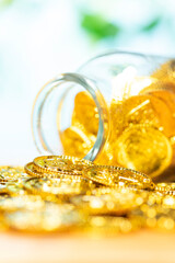 ガラス瓶に入れたたくさんの金貨の貯金イメージ