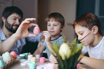Obraz na płótnie Canvas father and kids painting eggs for easter