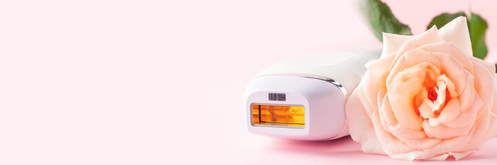 Home spa accessories -  photoepilator on pink  background. Apparatus and rose as a symbol. Banner. Copy space