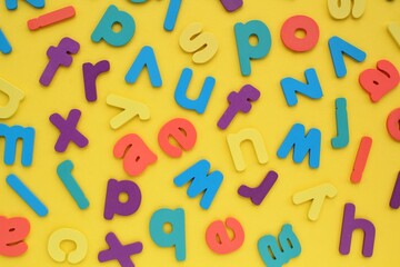 Pile of jumbled messy letters pattern on yellow background. Latin alphabet block colored letters. Dyslexia awareness confusion brain thinking psychology problem. English learning concept. Close up