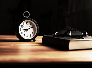 Alarm clock, glasses and a book on the table