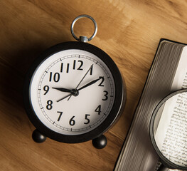Alarm clock, magnifying glass and book
