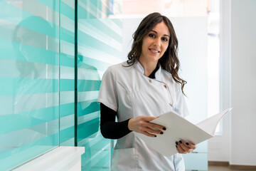 Happy nurse with documents standing at clinic