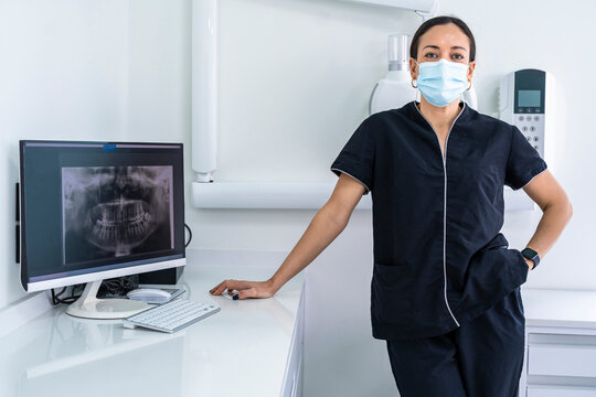 Doctor wearing surgical mask standing by desk at clinic