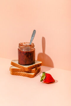 Homemade strawberry jam with slices of bread against peach background