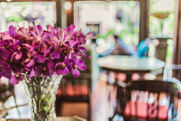 Decorative orchid flower bouquet in a slim clear glass vase on cafe