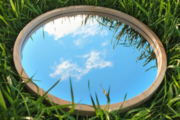 Obraz na płótnie Canvas Cloudy Blue Sky Reflection in Round Wood Mirror on Summer Field with Green Grass. Nature Concept. Earth Day. Save Environment. Peace. Ecology Protection. Climate Change, Global Warming Effect Problem