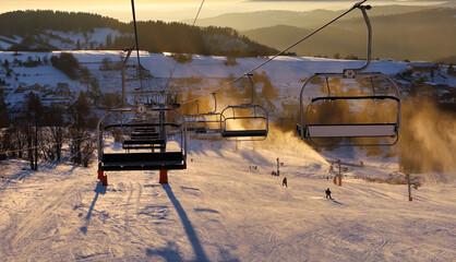 ski resort, skiers on the ski lift, white snow pine trees at pink sunset or dawn, Krahule Slovakia
