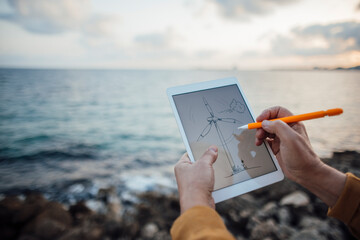 Hands of senior man drawing wind turbine on tablet PC with digitized pen