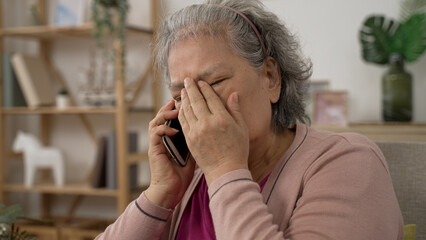 shoulder shot of a sad asian grandma covering her face in agony on receiving a terrible news on the...