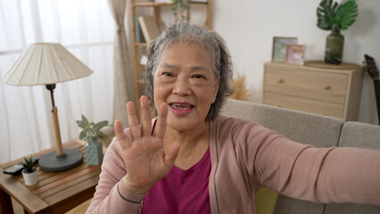 mobile cam view of a happy asian elderly woman waving hand and talking with a smile during a...