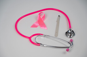  Pink stethophonendoscope, satin ribbon and scalpel on white background. 