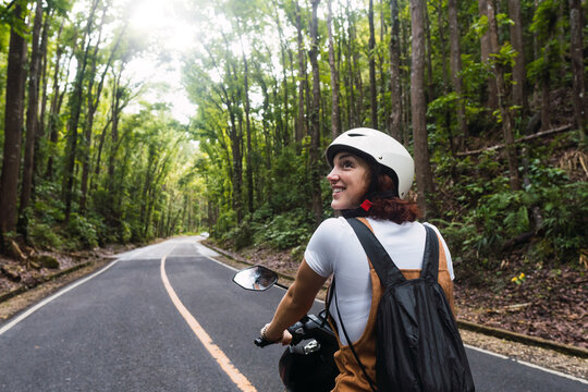 Happy woman wearing helmet riding motorcycle on road