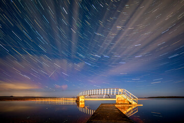 Star trails over illuminated bridge at night