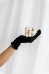 Beautiful handmade natural soy wax candle in the shape of a cube on a hand. Hand in black glove. 