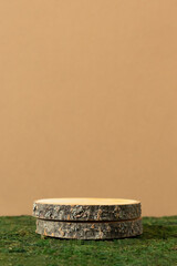 Fototapeta premium Wooden slice podium on green moss on beige background. Premium scene for product promotion, beauty, natural eco cosmetic. Empty showcase, display case.