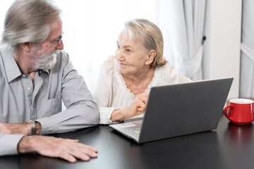 Older caucasian couple with tablet computer in living room at home