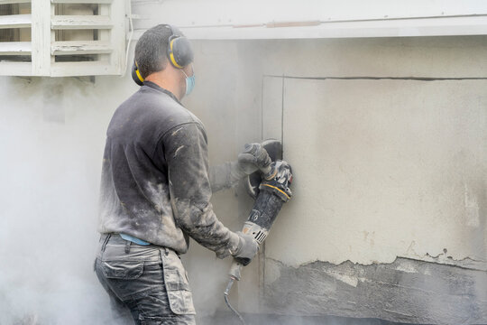 A man worker using a professional angle grinder to cut beton wall.