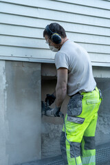 Adult male contractor using professional angle grinder for cutting wall.