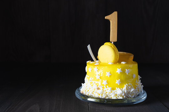 The number One on a yellow cake for an anniversary or birthday in a dark key.