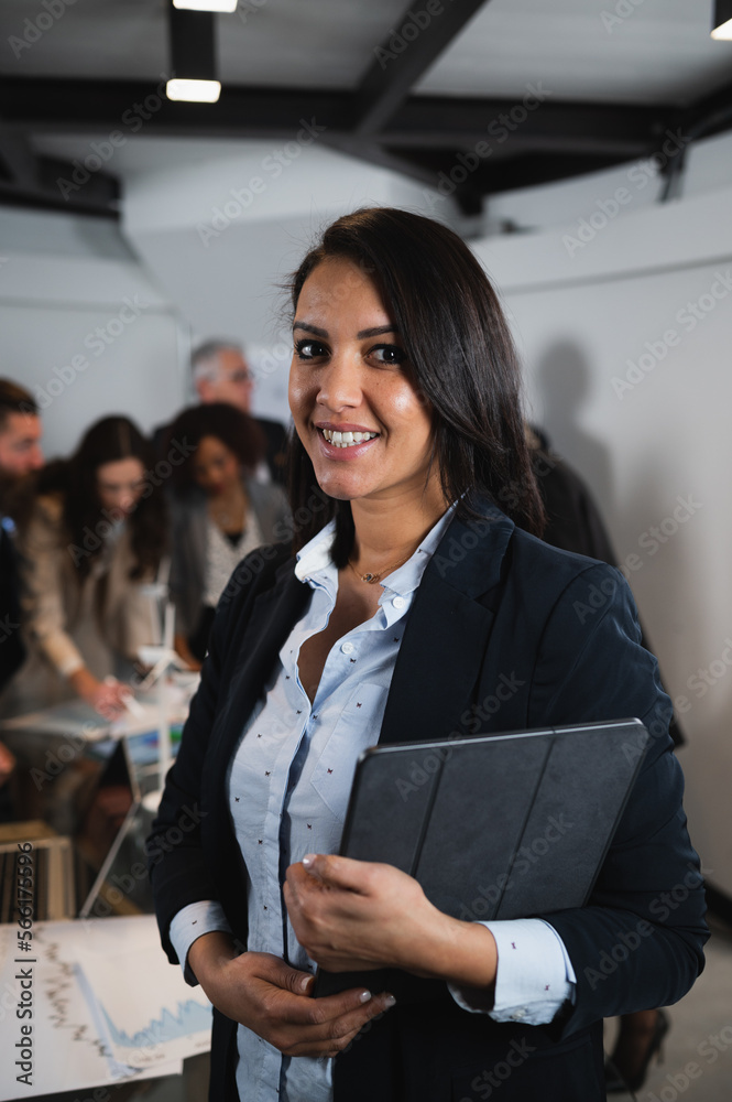 Wall mural vertical portrait elegant businesswoman smiling while looking at camera holding digital tablet. coll