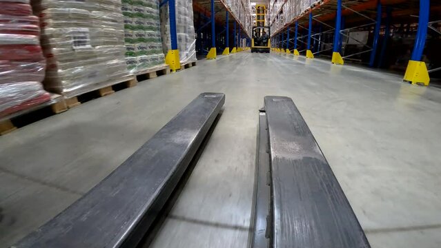 Large modern warehouse, view from the front of the forklift. The forklift rides through the warehouse close-up. Forklift work in a warehouse.
