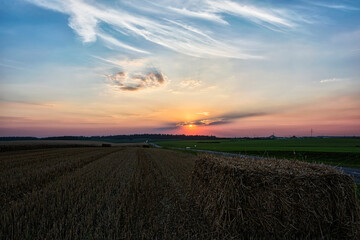 Landscape. The sun sets behind the feathery clouds.