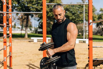 Obraz premium Muscular sportsman during weightlifting workout on sports ground