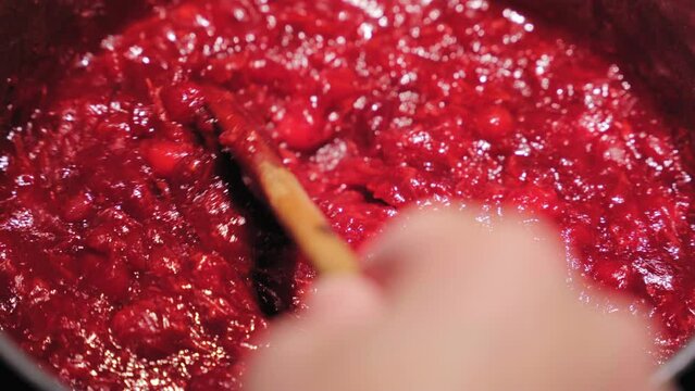 Mixing cranberry sauce with wooden spoon, close up view.
