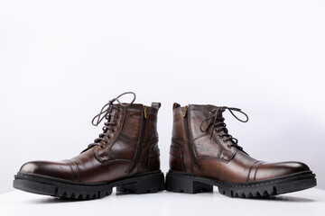A pair of brown colored leather boots on a white background.